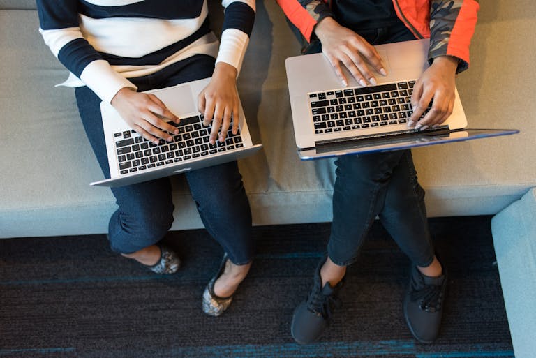 Two people working on laptop computers from above, showcasing collaboration in a tech environment.