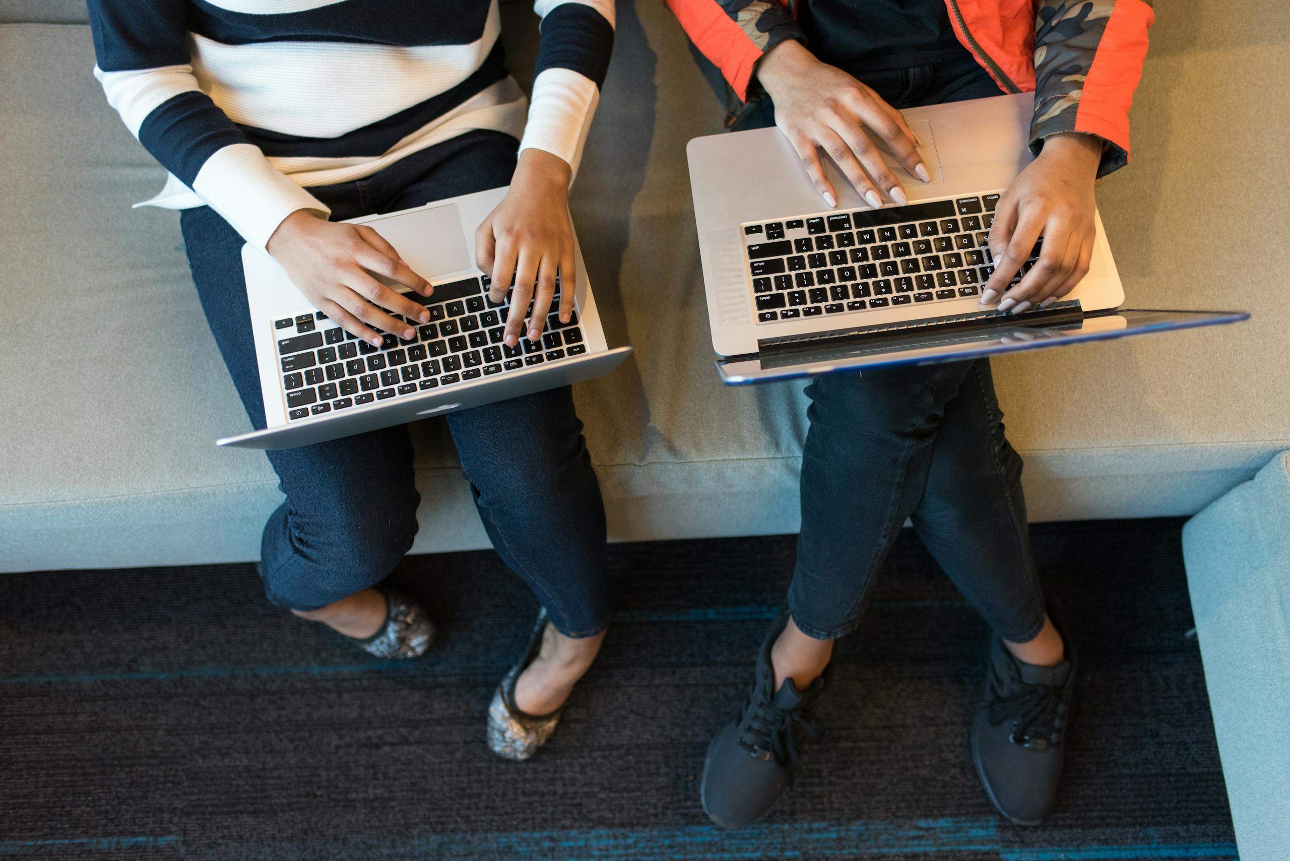 Two people working on laptop computers from above, showcasing collaboration in a tech environment.