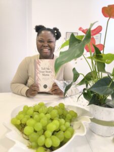 A Photo of myself holding a copy of Tell Me Your Story, Mama which is published by HDY Haus and written by yours truly, Mary Mojisola Job